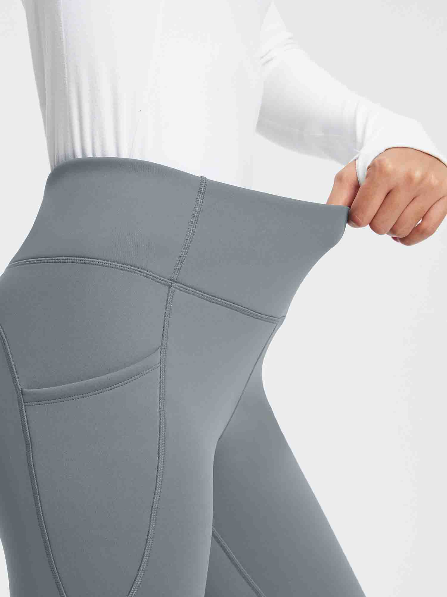 Gray thermal fleece yoga leggings with high waist and side pockets, showing fabric stretch. #color_Dark Gray
