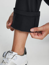 Black women's fleece-lined golf pants with detailed ankle cuff and white golf shoe. #color_Black