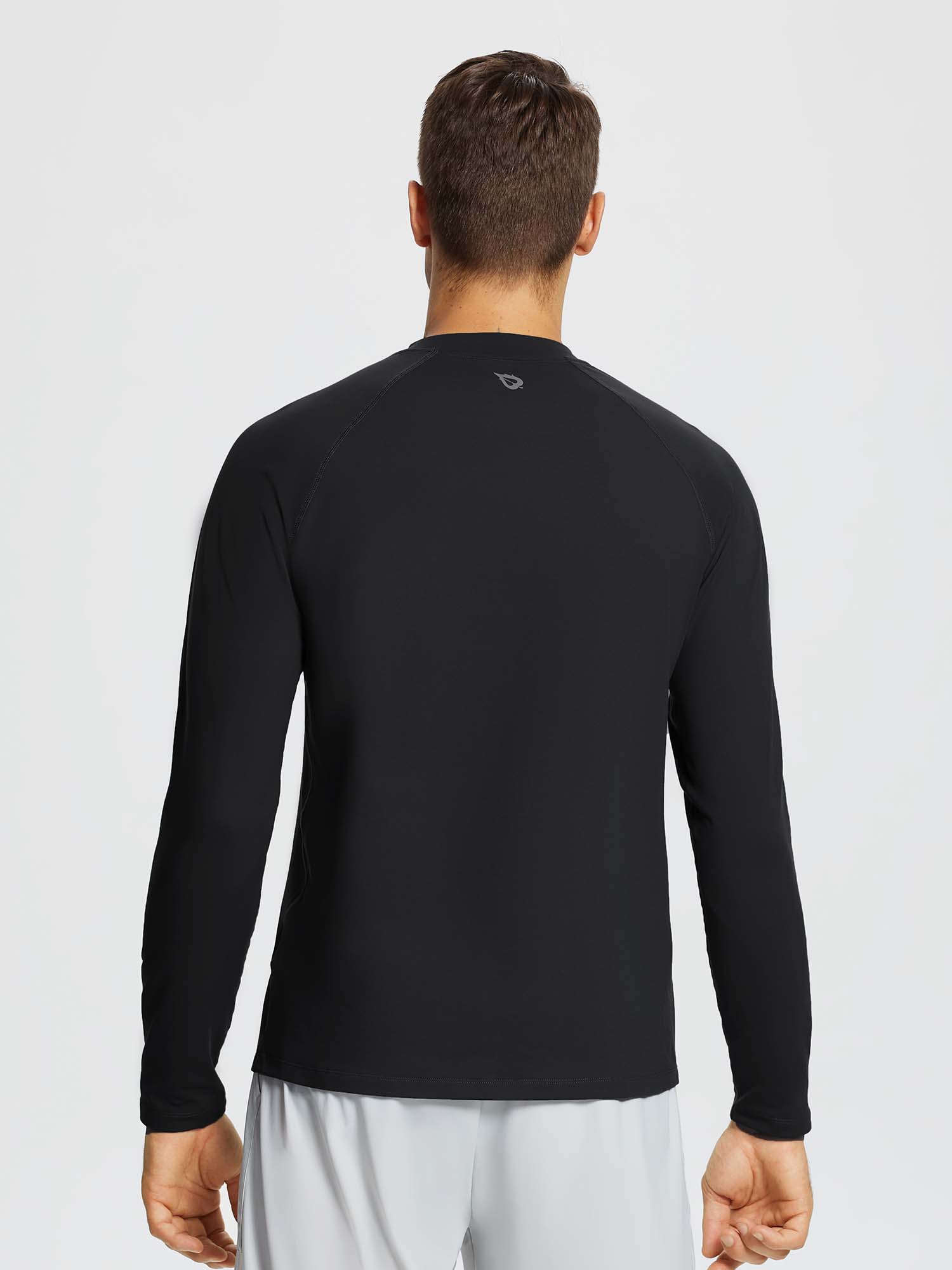 Man wearing a black long-sleeve knit fleece running top with a subtle gray logo on the back. #color_Black