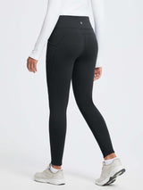 Black 27" thermal fleece high-waist yoga leggings with side pockets and a white long-sleeved top. #color_Black