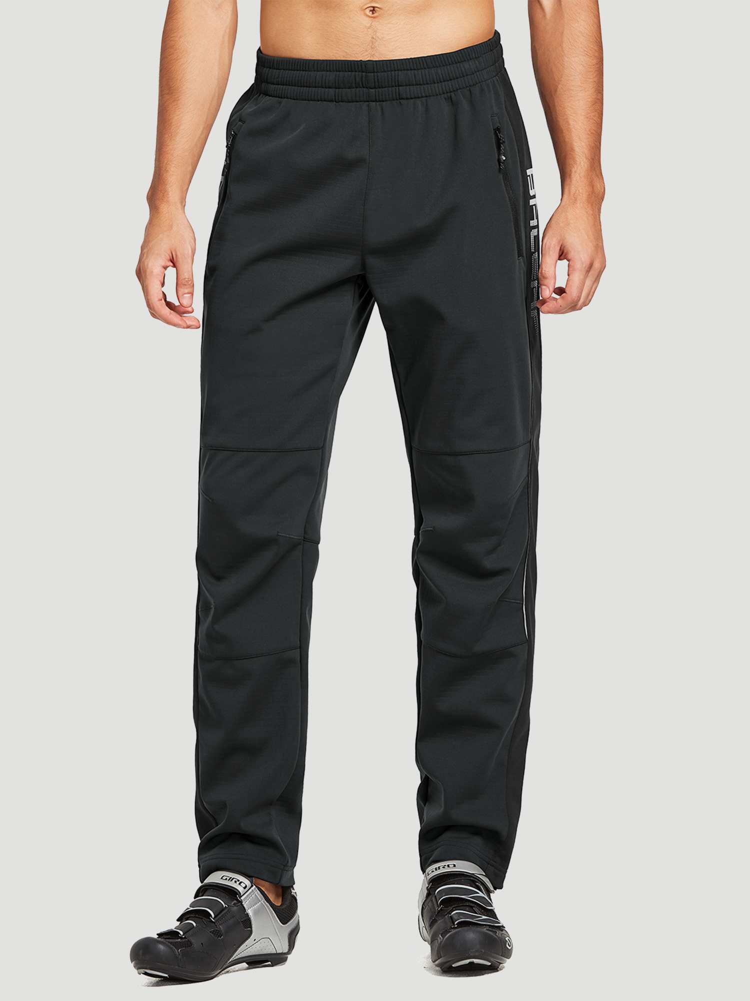 Men's black knit fleece cycling pants with zip pockets and reflective ankle cuffs, shown with cycling shoes. #color_Black