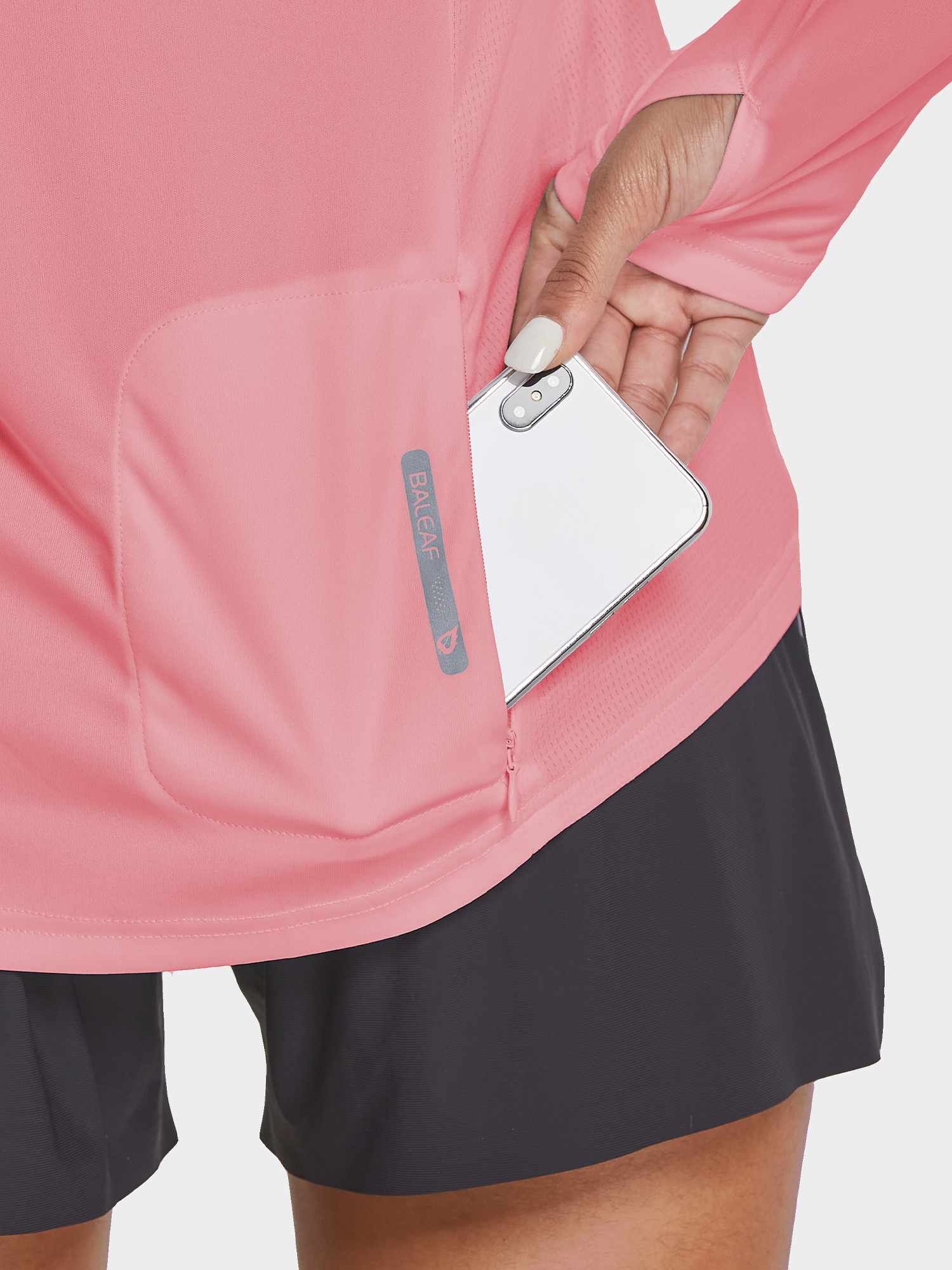 Woman's pink UPF 50+ hiking shirt with zippered pocket holding a smartphone and thumbholes on sleeves. #color_Pink