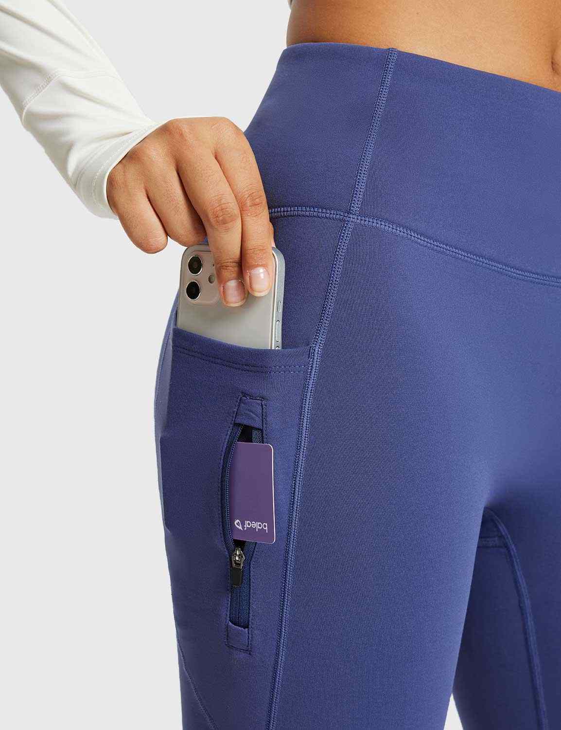 Navy blue thermal flare yoga pants with phone and zip pocket. High-waisted activewear with fleece lining.