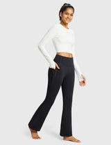 Woman wearing black thermal warm flare pants with pockets and a white long-sleeved crop top. #color_Black