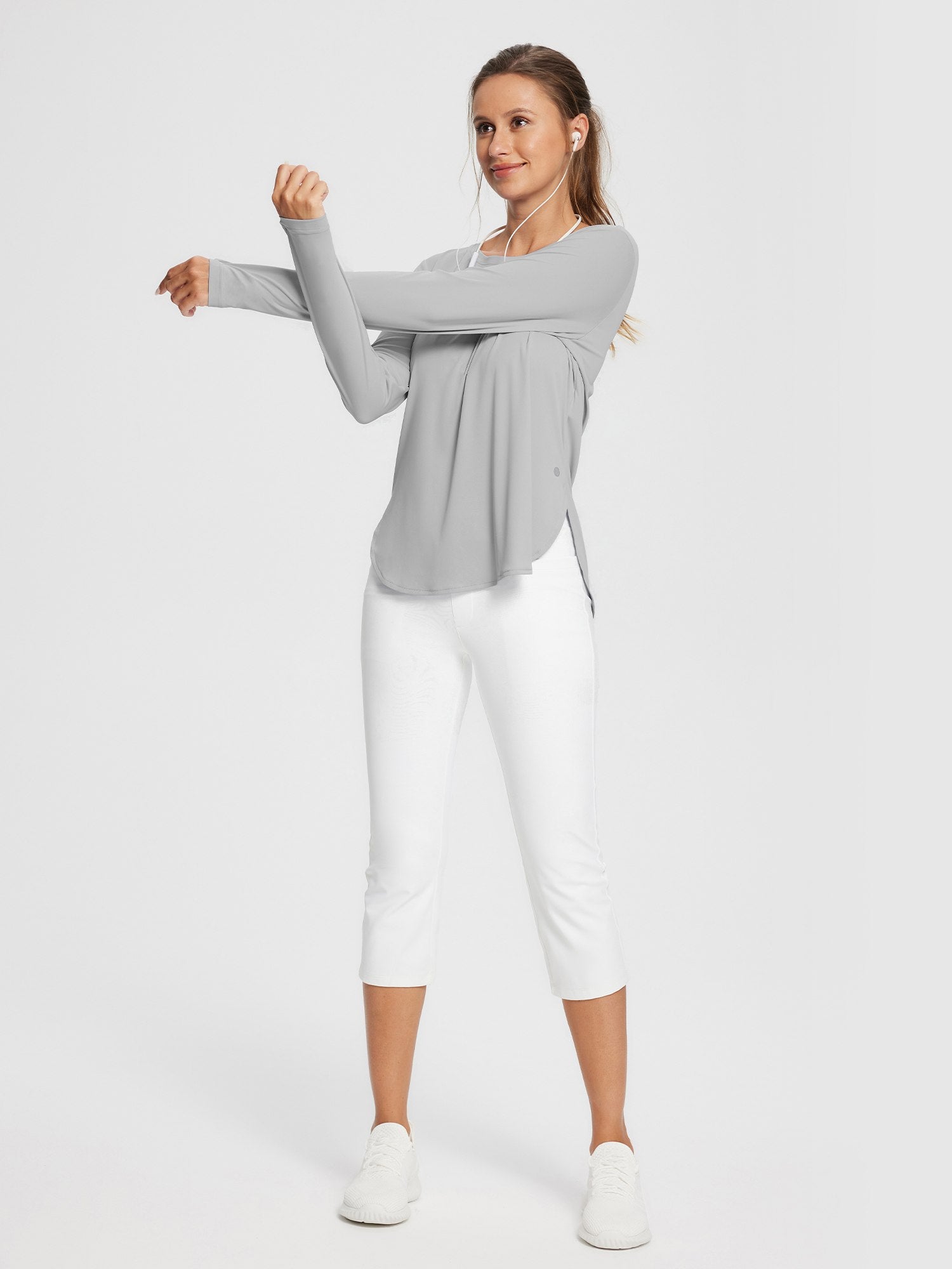 Woman stretching arms in a light gray long-sleeve UPF 50+ t-shirt and white capri pants. #color_Light Gray