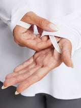 Woman's hands adjusting thumbhole on white long sleeve t-shirt for outdoor activities. #color_White