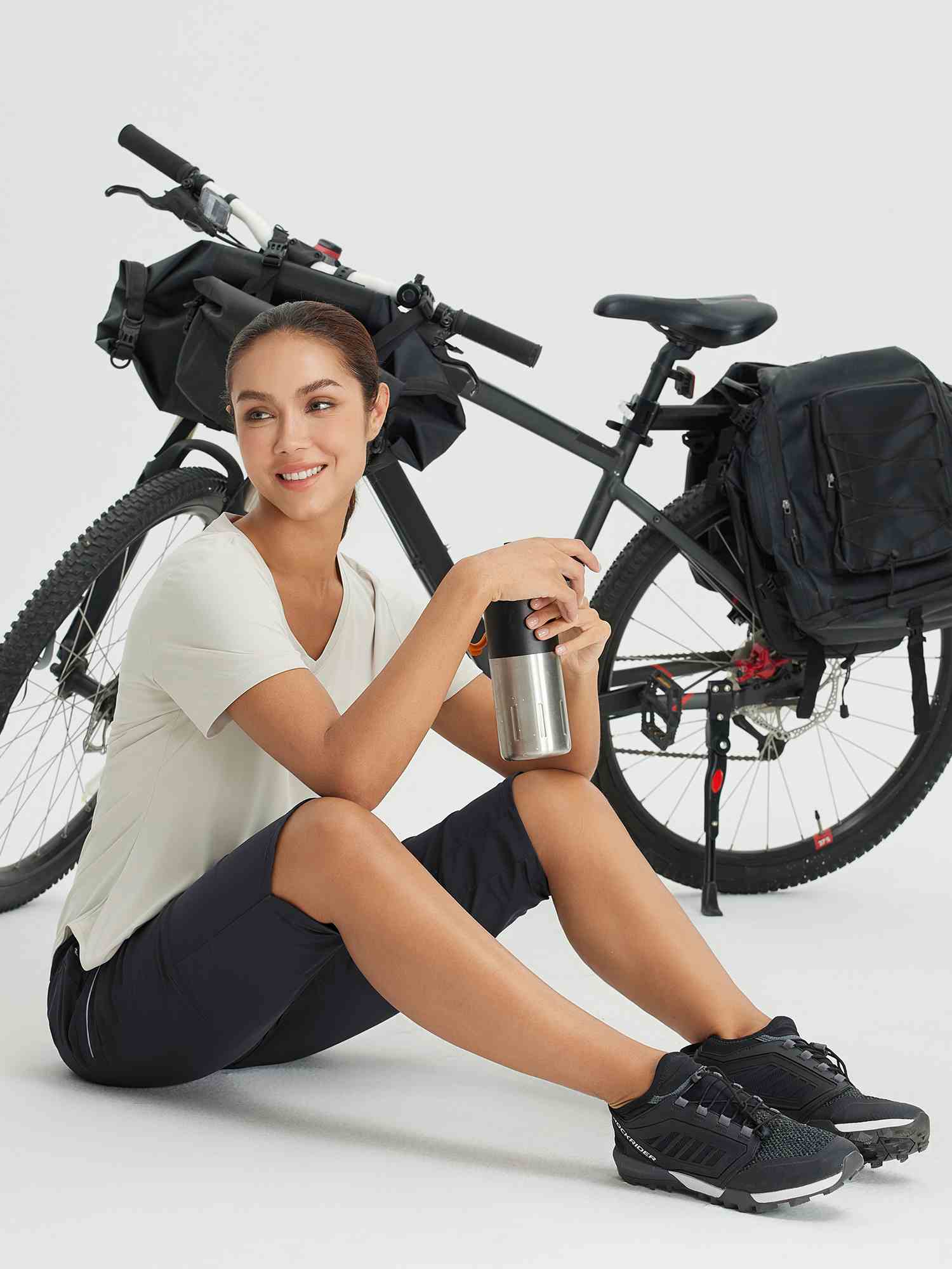 Woman in dark capri pants and t-shirt with a bicycle and water bottle #color_Black
