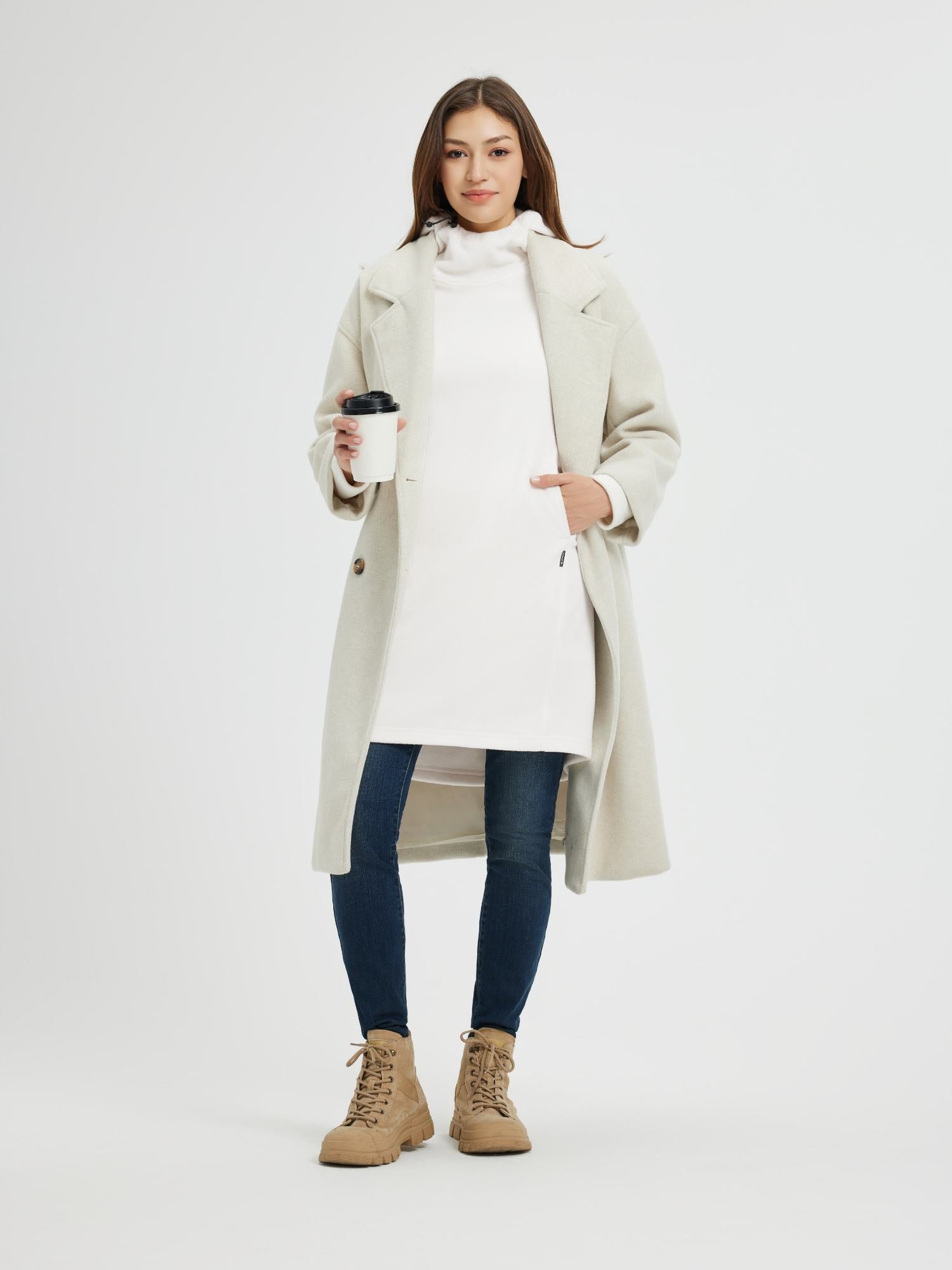 Woman wearing a white hooded fleece dress, jeans, and a cream coat, holding a coffee cup. #color_White