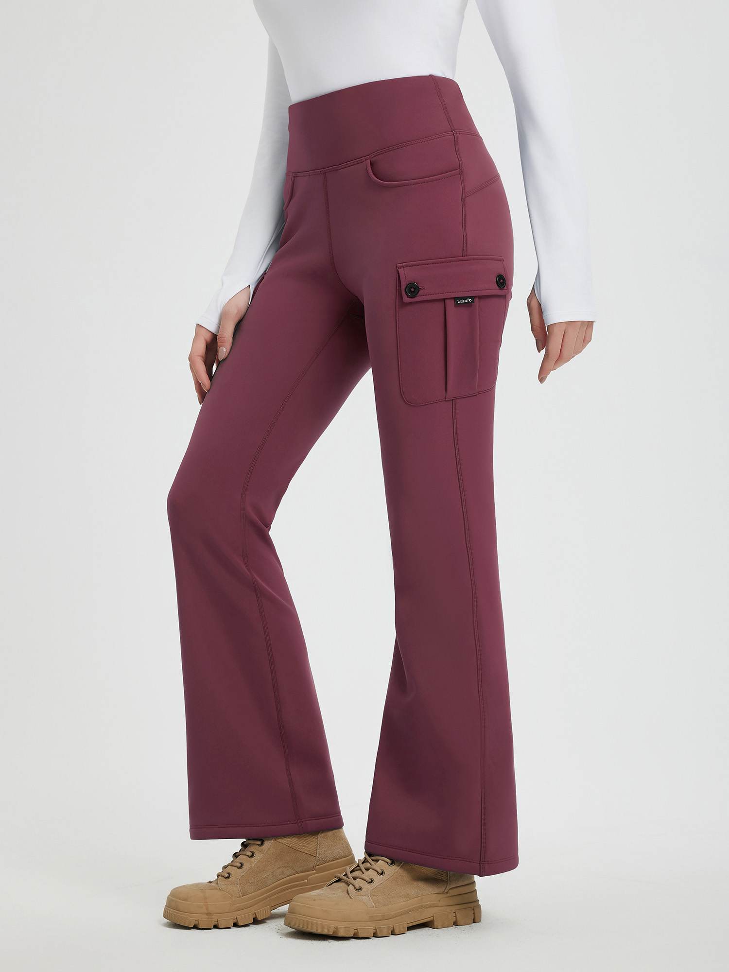 Woman wearing wine red, thick fleece, workwear flared pants with cargo pockets and brown boots. #color_Wine Red