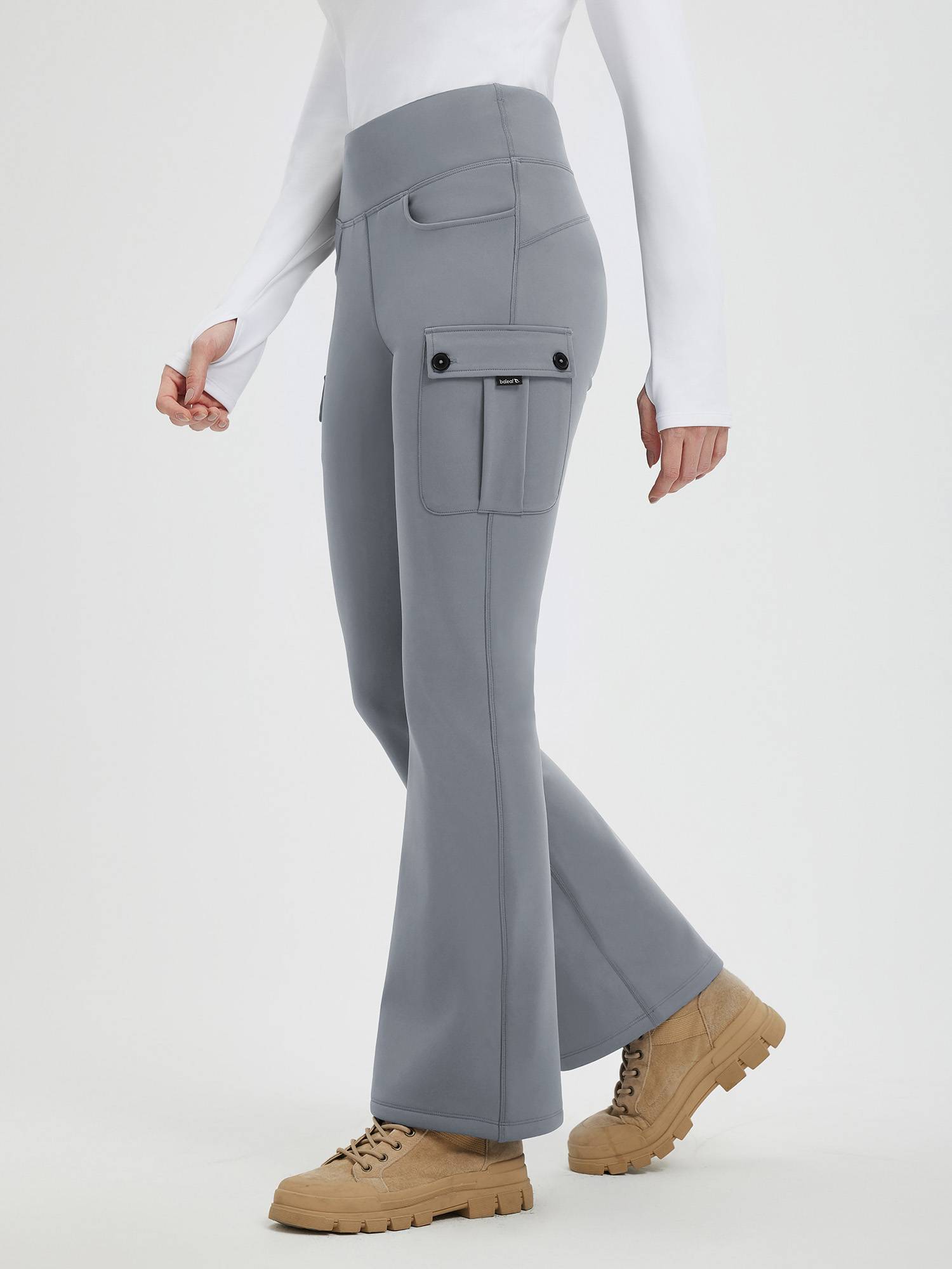 Woman wearing gray fleece-lined flared workwear pants with cargo pockets and a white long-sleeved shirt. #color_Dark Gray
