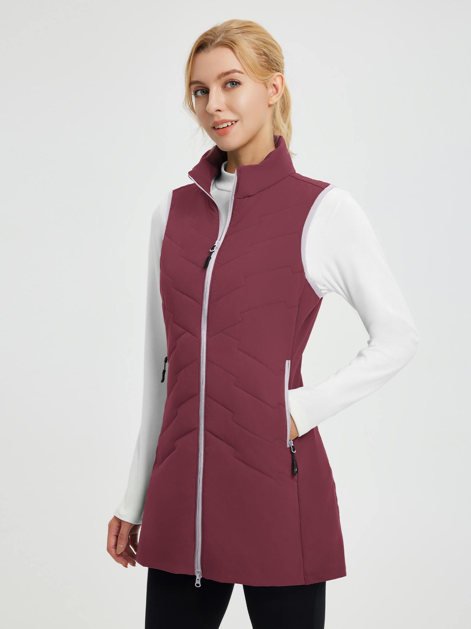 Wine-red women's mid-length woven hiking vest, silver zipper, side pockets. Worn over white shirt.