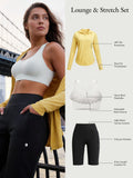 Lounge & Stretch Set: yellow UPF 50+ jacket with thumbholes, white sports bra, black high-waist shorts with pockets.