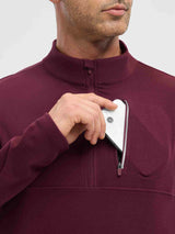 Man placing a smartphone into the zippered chest pocket of a maroon fleece running long-sleeve t-shirt. #color_Wine Red