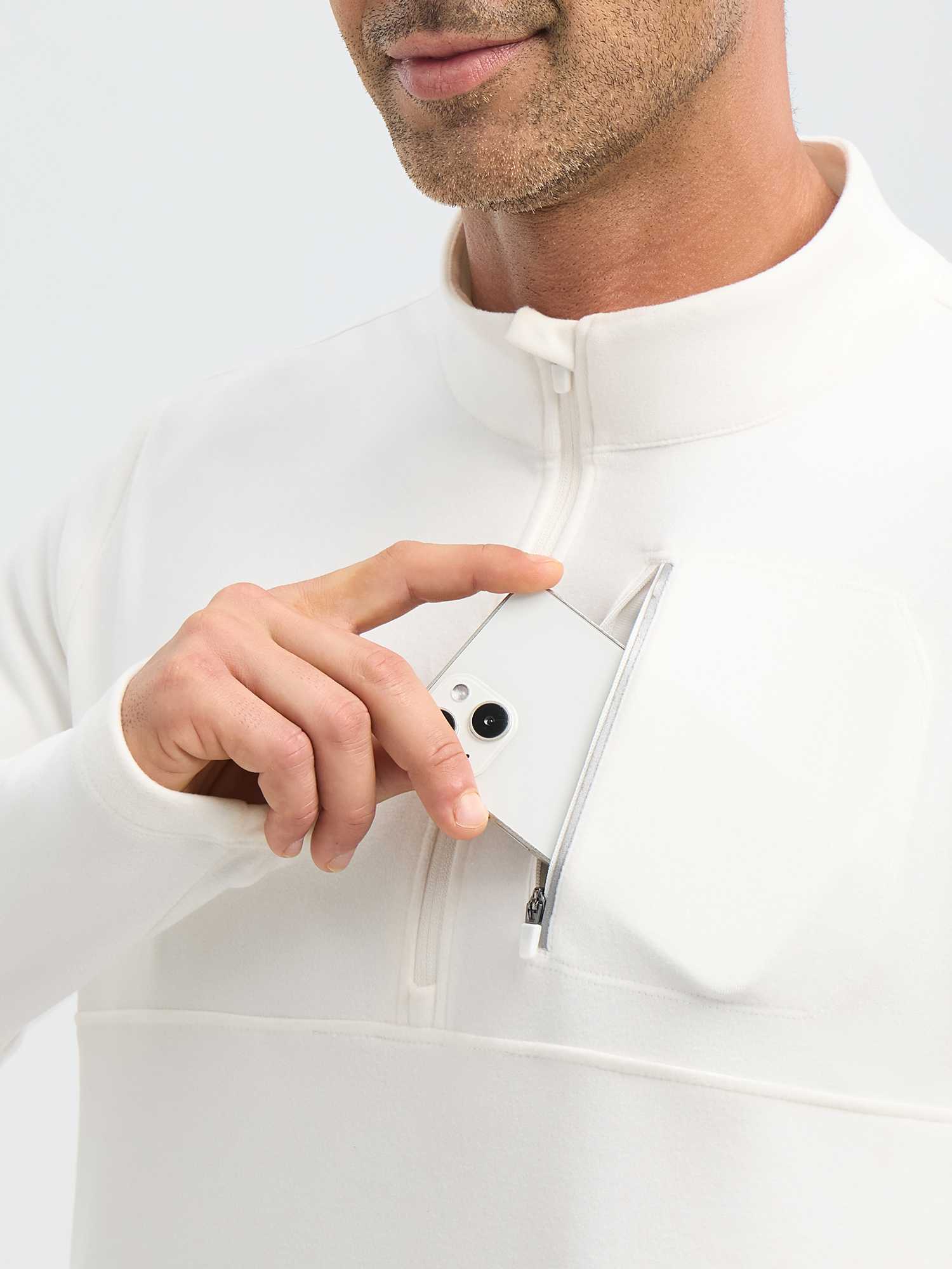 Man puts phone into chest zip pocket of white men's running fleece half-zip long-sleeve shirt. #color_Star White