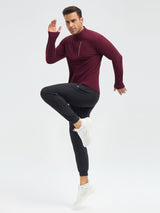 Man in maroon half-zip running shirt with chest pocket & thumbholes, black joggers, white sneakers. #color_Wine Red