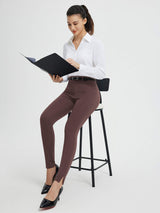Woman in brown high-waisted yoga business pants and white shirt, holding a black folder. #color_Dark Brown