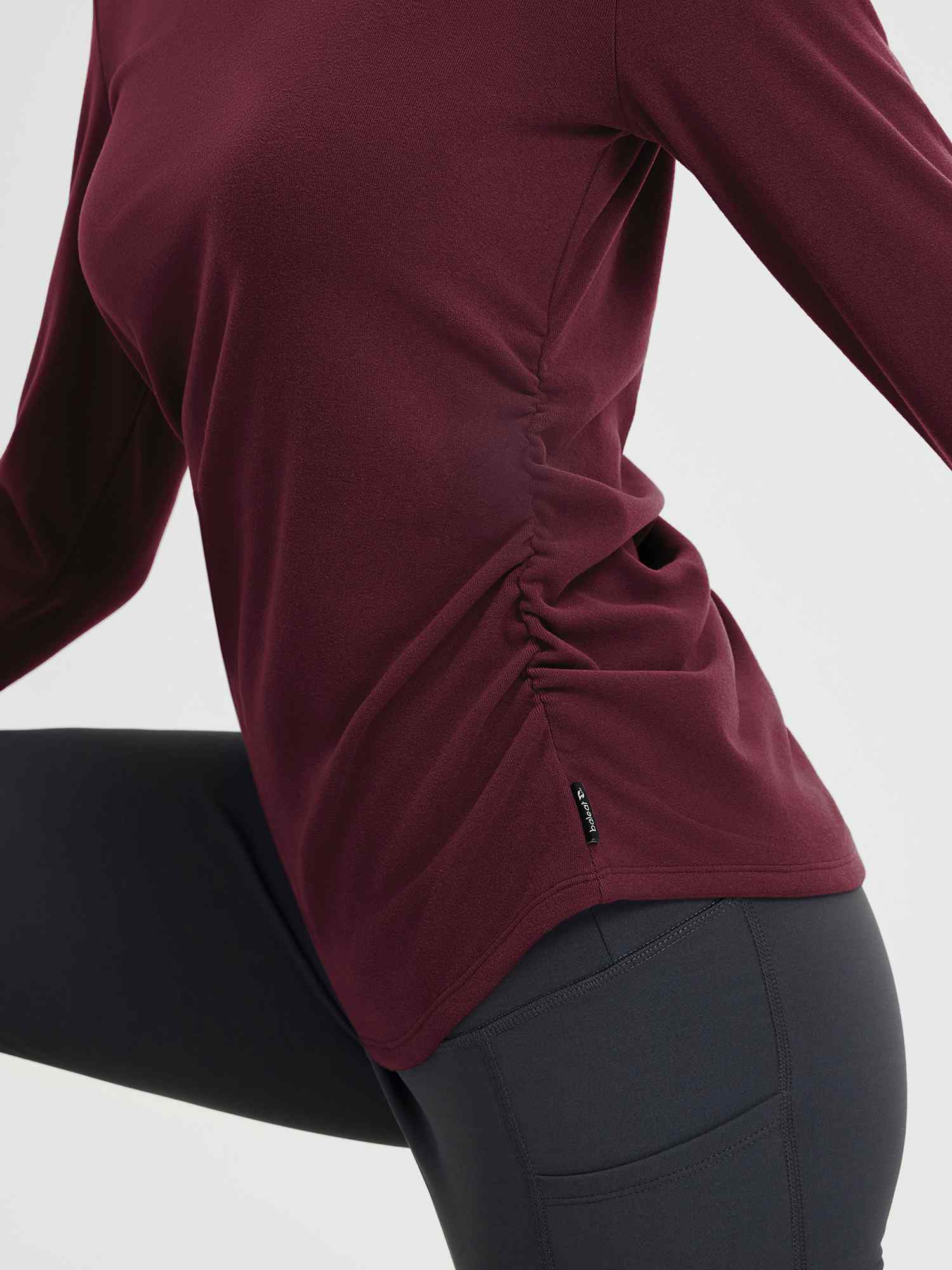 Burgundy long-sleeve yoga top with side ruching and thumbholes, paired with dark grey leggings. #Color_Wine Red