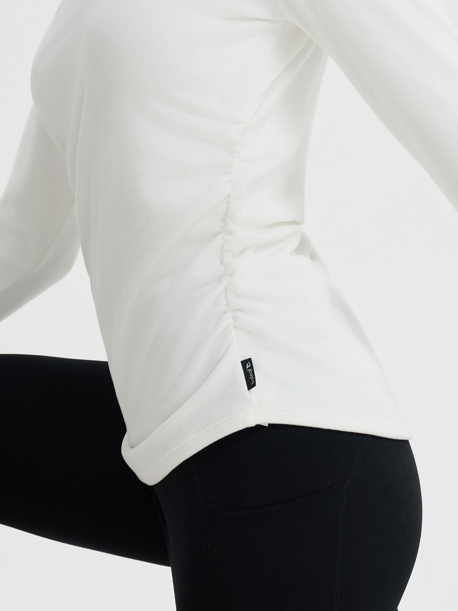 White long-sleeve yoga top with side ruching and BALEAF logo on the hem, paired with black leggings. #Color_Star White