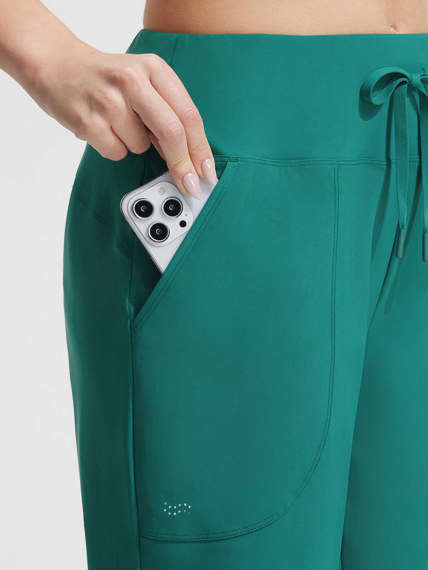 Baleaf dark green UPF 50+ high-rise board shorts: hand puts phone in pocket. #color_Teal Green
