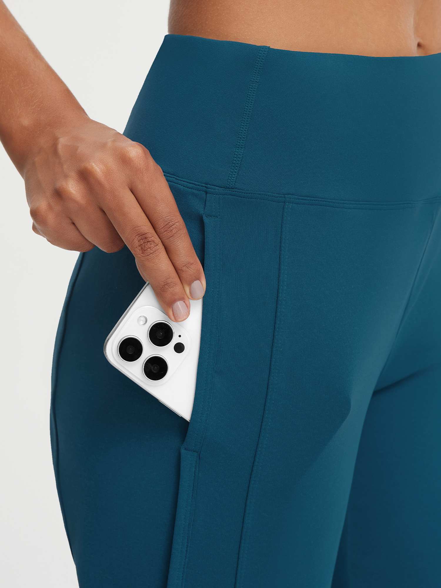 Teal Baleaf high-rise 17" capri pants featuring a large side pocket holding a smartphone. #color_Deep Blue