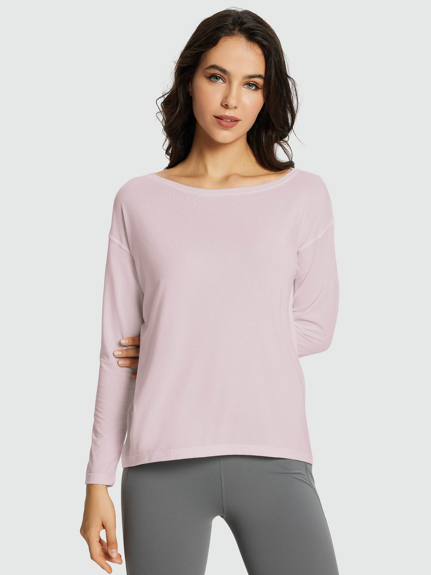 Woman wearing a light pink long-sleeve workout t-shirt with a boat neckline and grey leggings. #color_Light Purple