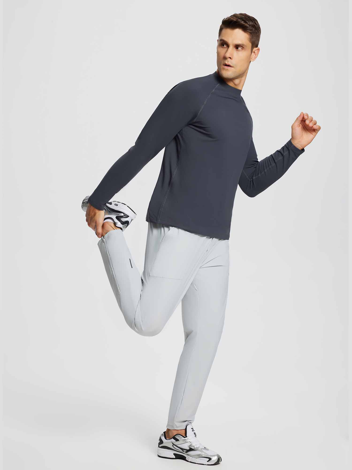 Man in dark gray half-mock knit fleece running top and light gray running pants stretching. #color_Dark Gray