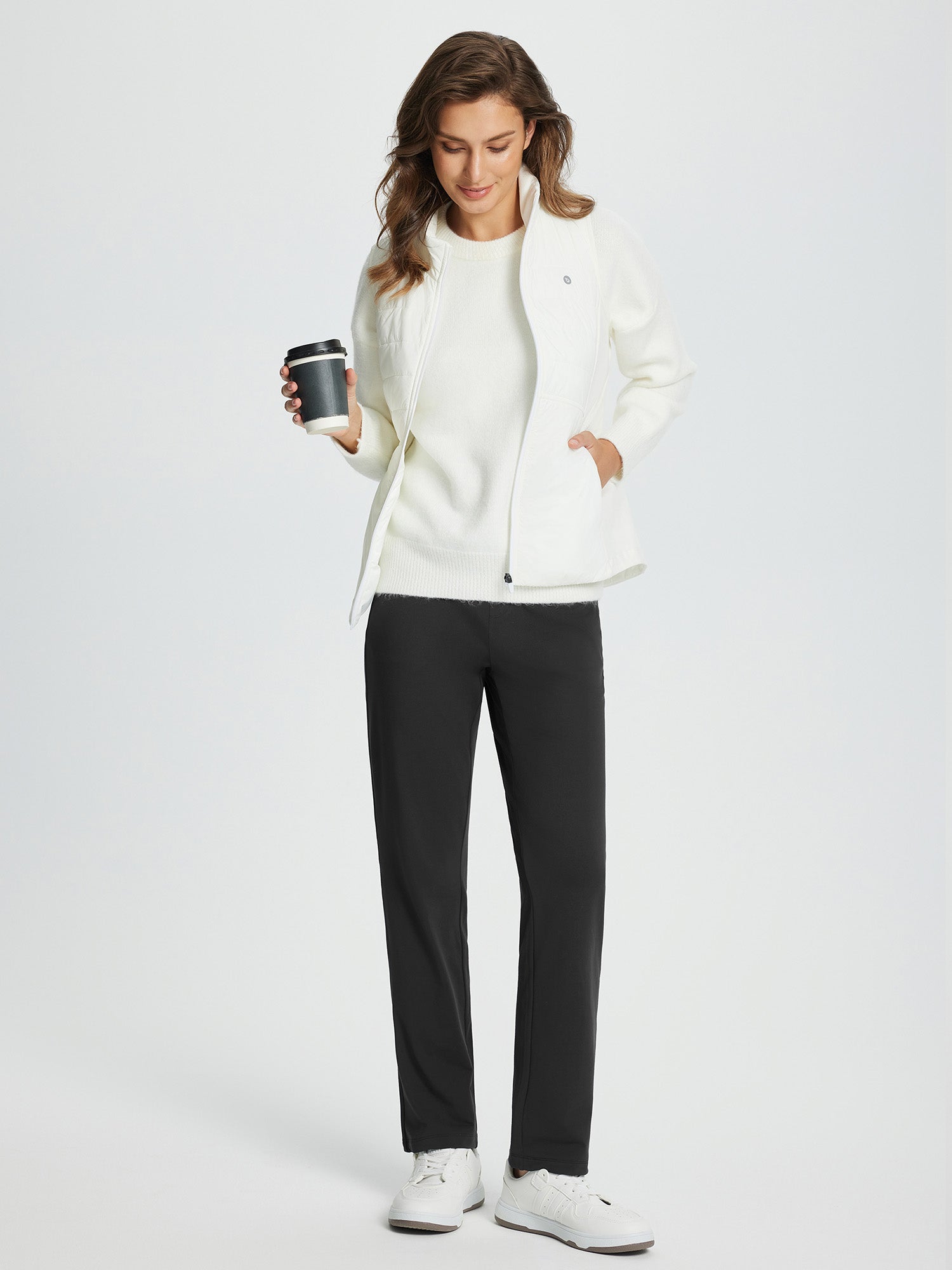Woman in black fleece-lined golf pants and white sweater, holding a coffee cup. #color_Black