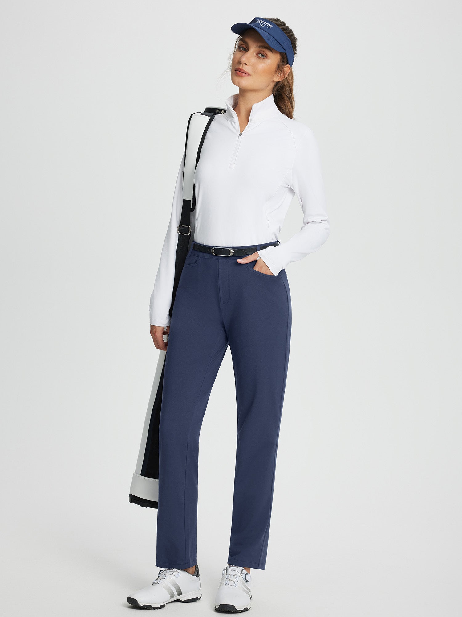 Navy blue women's fleece-lined straight-leg golf pants with white shirt and golf bag. #color_Navy Blue
