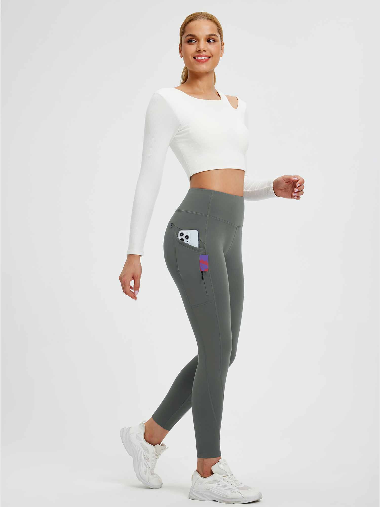 Woman in dark grey 25" fleece-lined yoga leggings with side pockets, walking. #color_Dark Gray