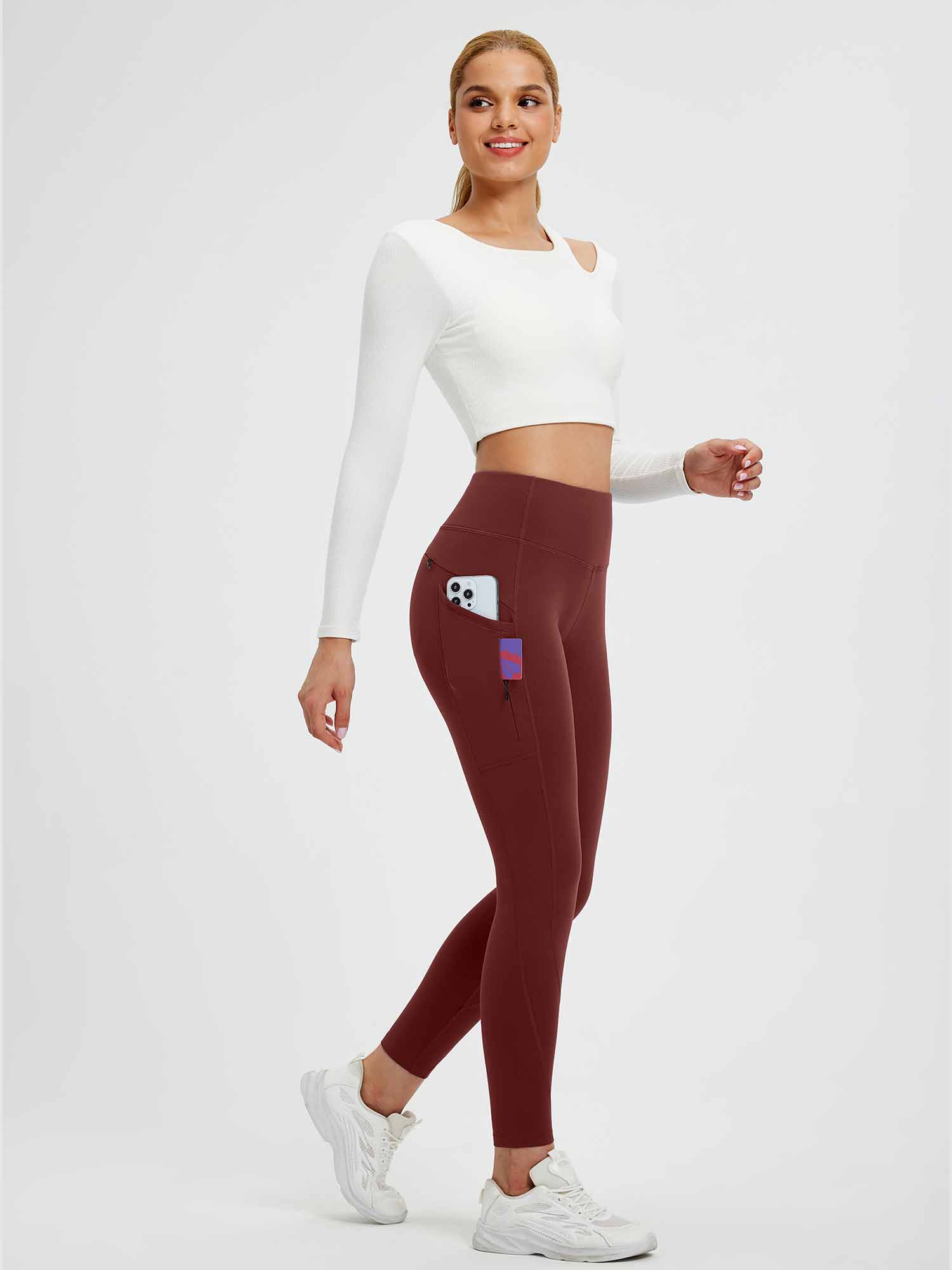 Woman wearing maroon fleece-lined yoga leggings with side pockets and a phone stored inside. #color_Wine Red