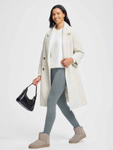 Woman in grey 27" thermal fleece yoga leggings, white sweater, cream coat, black bag, and tan boots. #color_Dark Gray