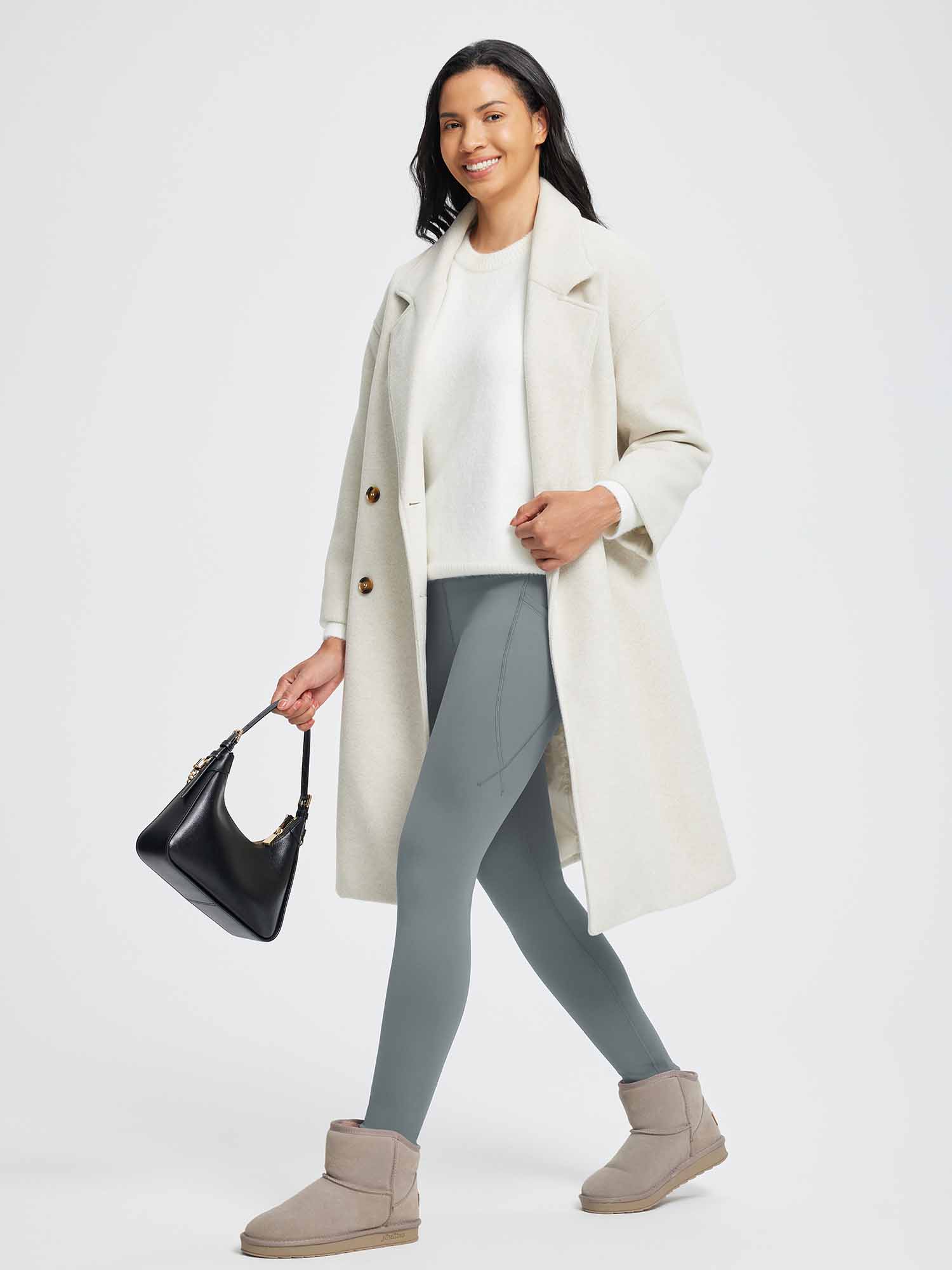 Woman in grey 27" thermal fleece yoga leggings, white sweater, cream coat, black bag, and tan boots. #color_Dark Gray