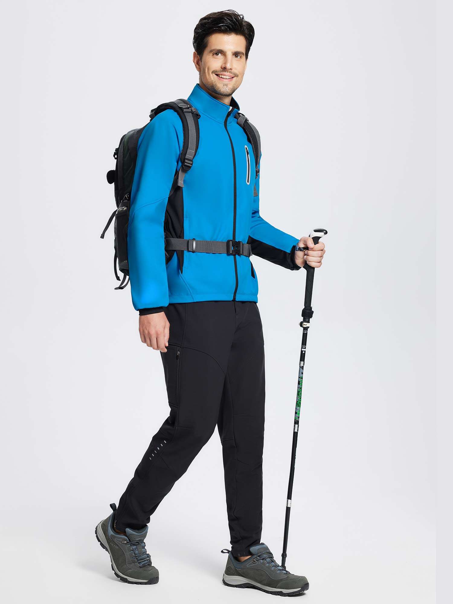 Man in blue thermal cycling jacket, black pants, backpack, and trekking pole. #color_Quartz Blue