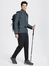 Man in dark gray thermal cycling jacket, black pants, and hiking shoes holding a trekking pole. #color_Dark Gray