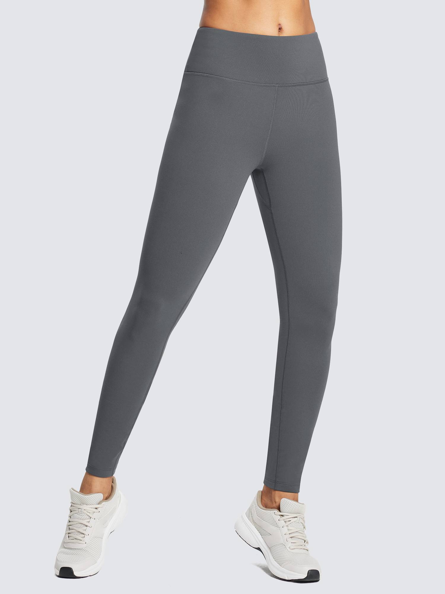 Woman in dark gray fleece-lined waterproof skinny running leggings and white sneakers.