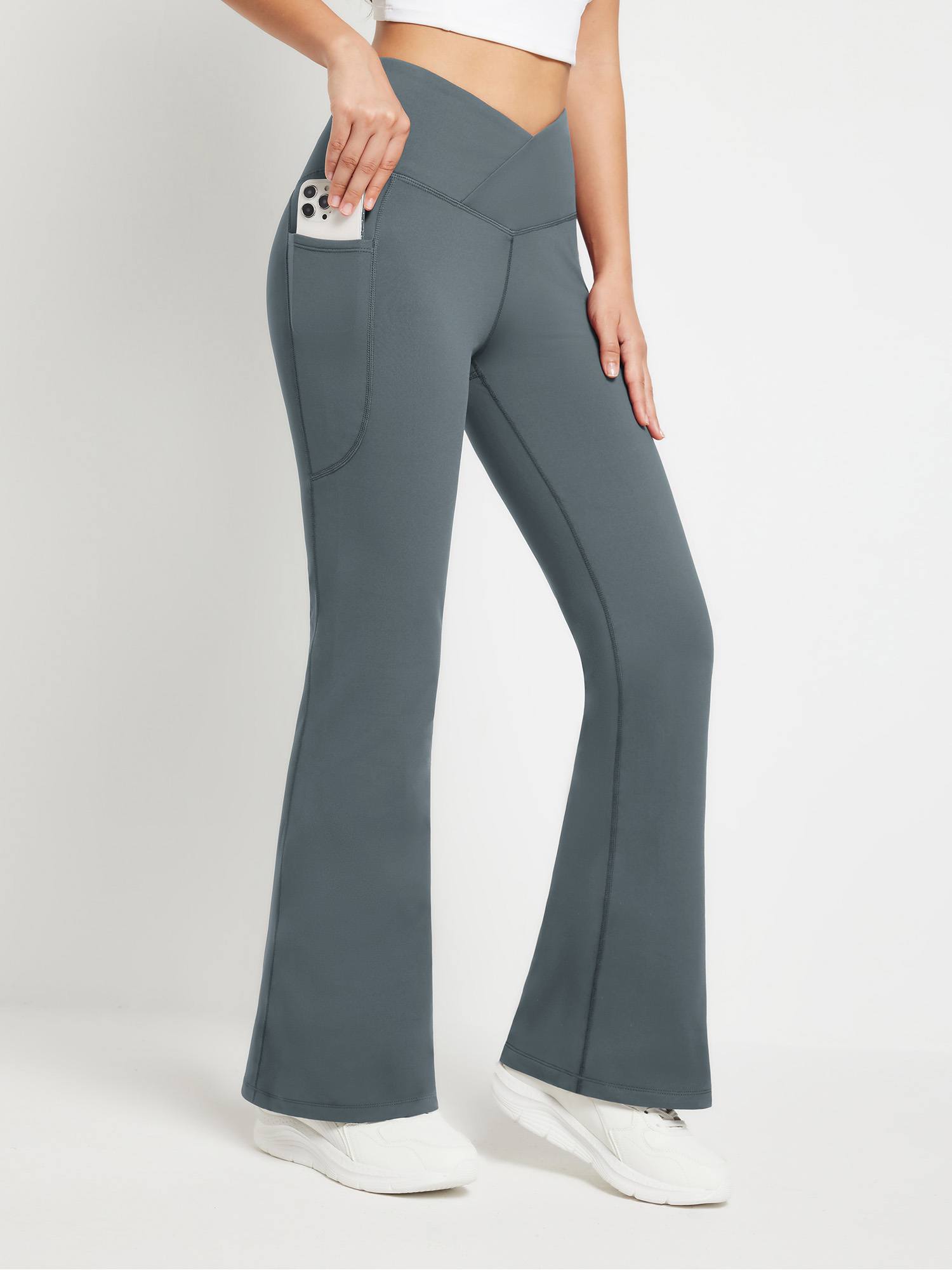 Crossover waist fleece flare pants in dark gray with side pockets holding a smartphone. #color_Dark Gray