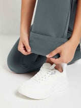 Dark gray fleece-lined flare pants held by hands, showing soft interior. White sneaker visible.