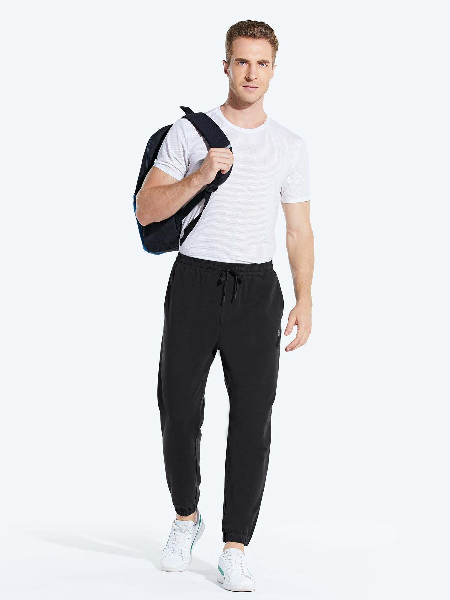 Black men's cotton joggers with drawstring and cuffed ankles, worn with a white tee and backpack. #color_Black/Gray