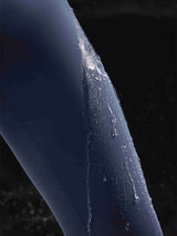 Close-up of navy blue water-resistant 3/4 thermal ski leggings with water droplets beading on the fabric. #color_Navy Blue