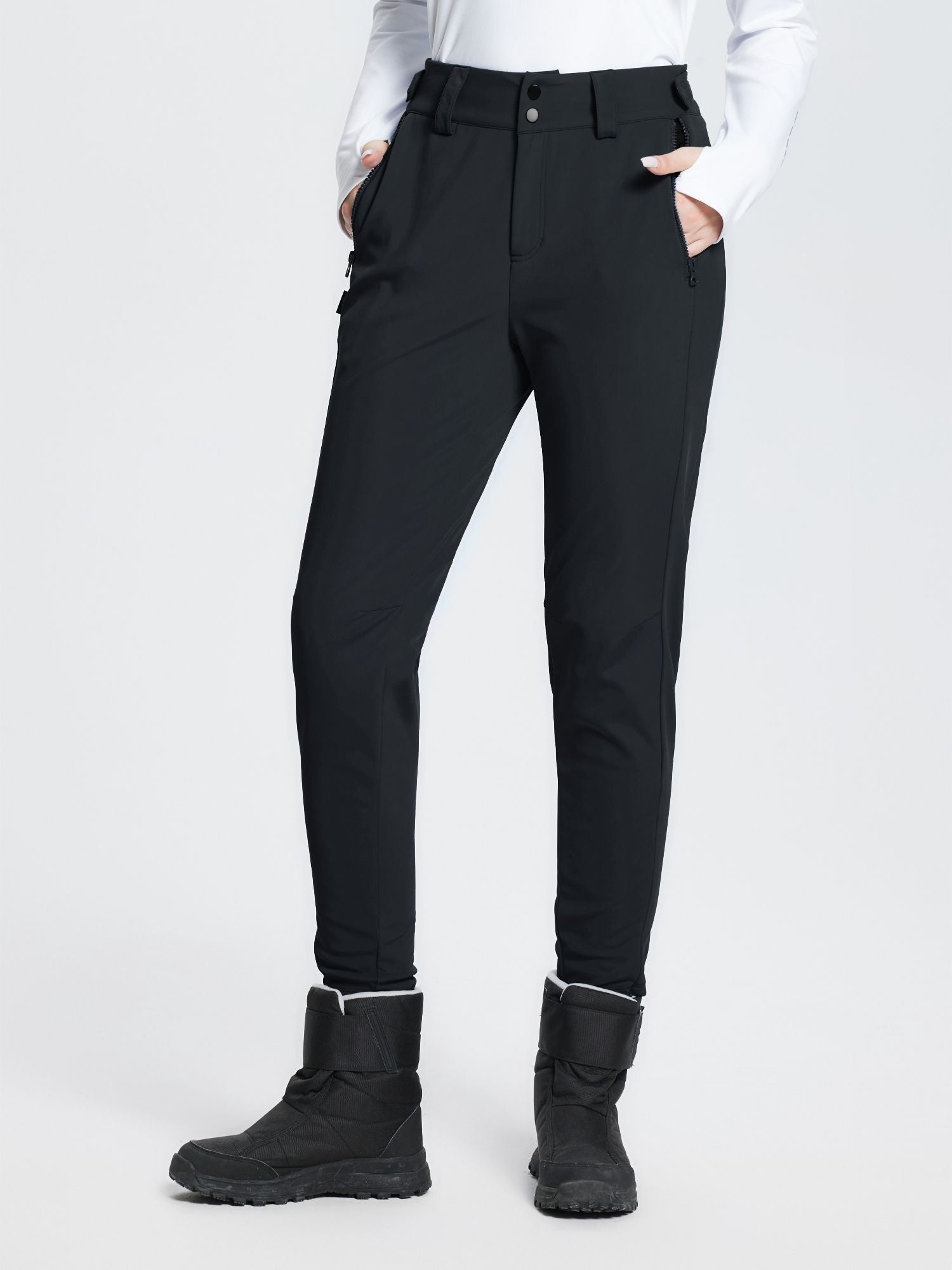 Black stretch knit slim-fit ski pants with zippered pockets and fuzzy ankle trim, worn with snow boots. #color_Black