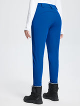 Woman wearing blue stretch knit slim-fit ski pants and a white long-sleeve shirt with black snow boots. #color_Quartz Blue