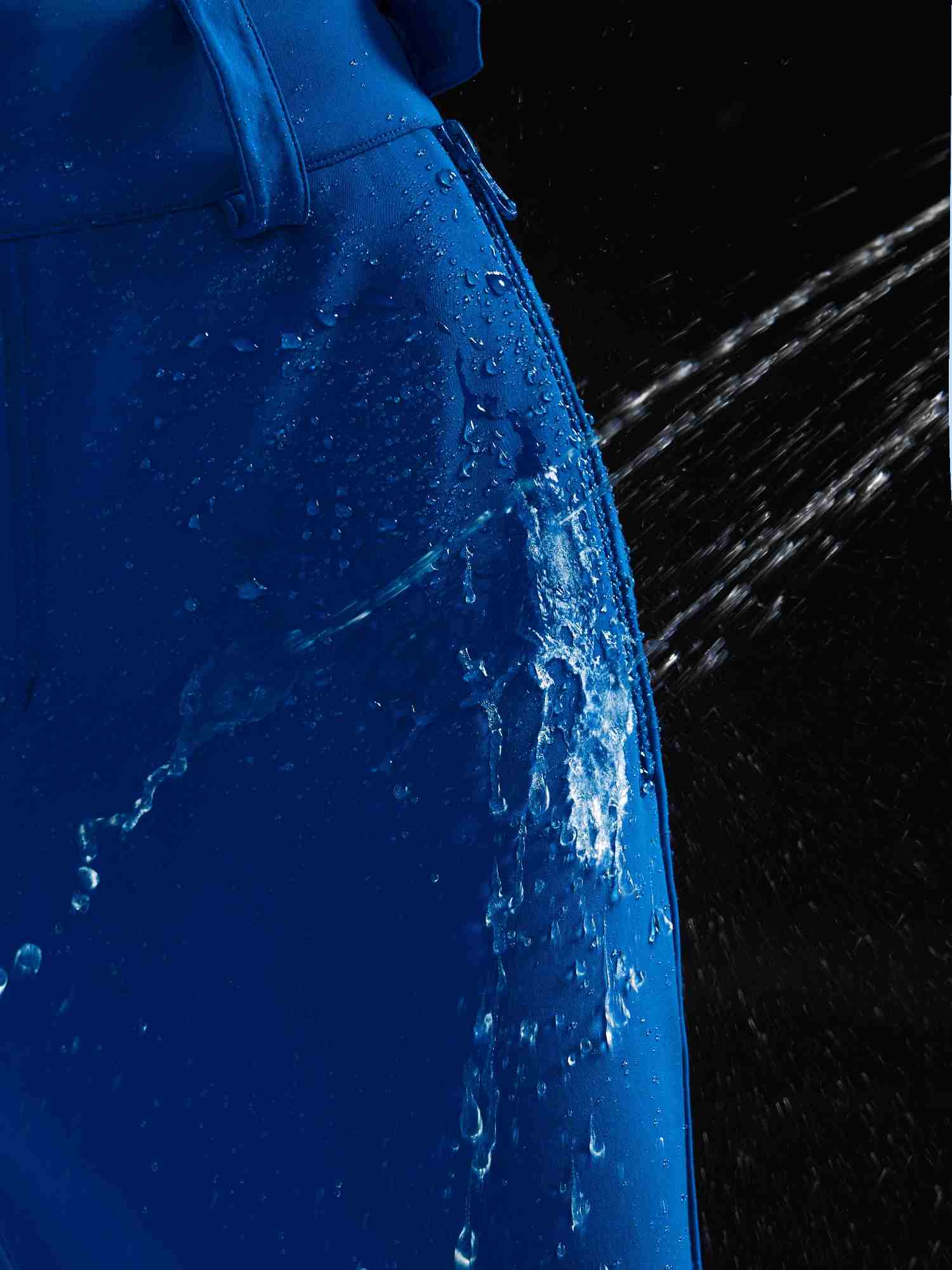 Water beading off royal blue stretch knit slim-fit ski pants, highlighting waterproof fabric. #color_Quartz Blue