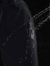 Dark gray ski pants with water beading, showing waterproof fabric. #color_Black