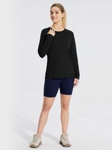 Black long-sleeve rash guard with navy blue athletic shorts and beige hiking boots on a woman. #color_Black
