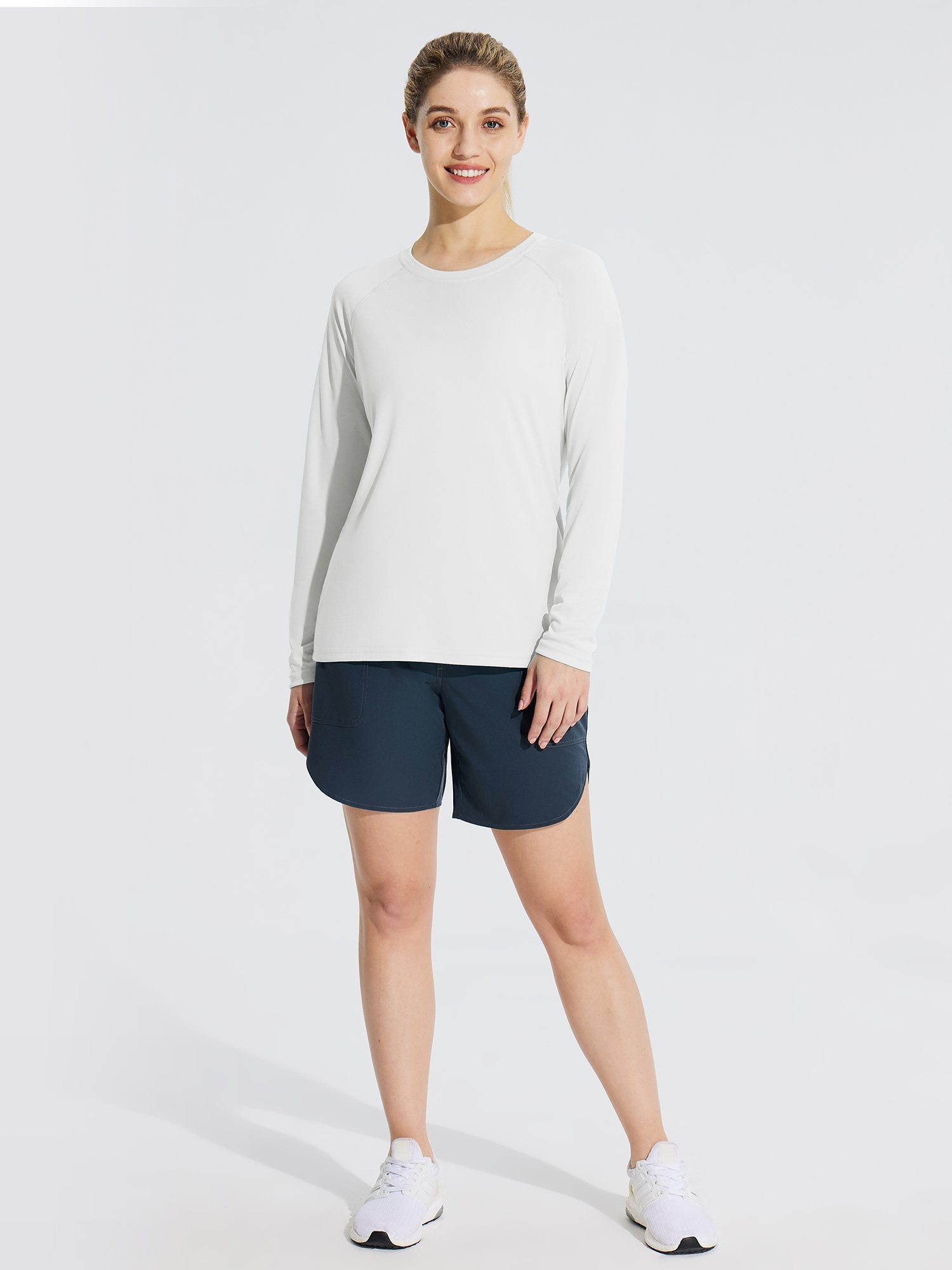 Woman in white UPF 50+ long sleeve rash guard and navy shorts, ideal for outdoor activities.