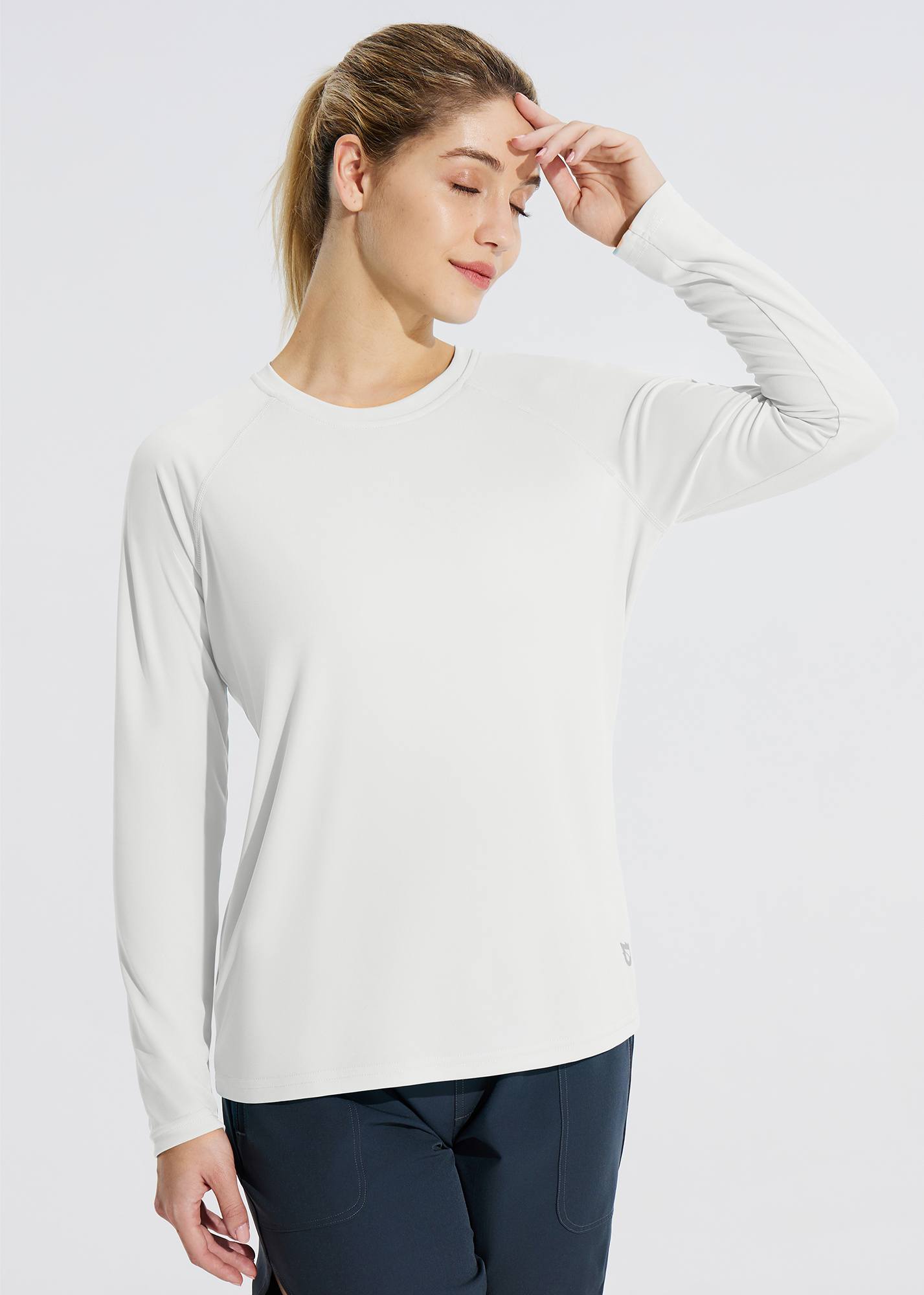 Woman wearing a white long sleeve rash guard with raglan sleeves and navy blue shorts. #color_White