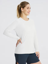 Woman wearing a white long sleeve rash guard and dark blue shorts, with her hand on her hip. #color_White