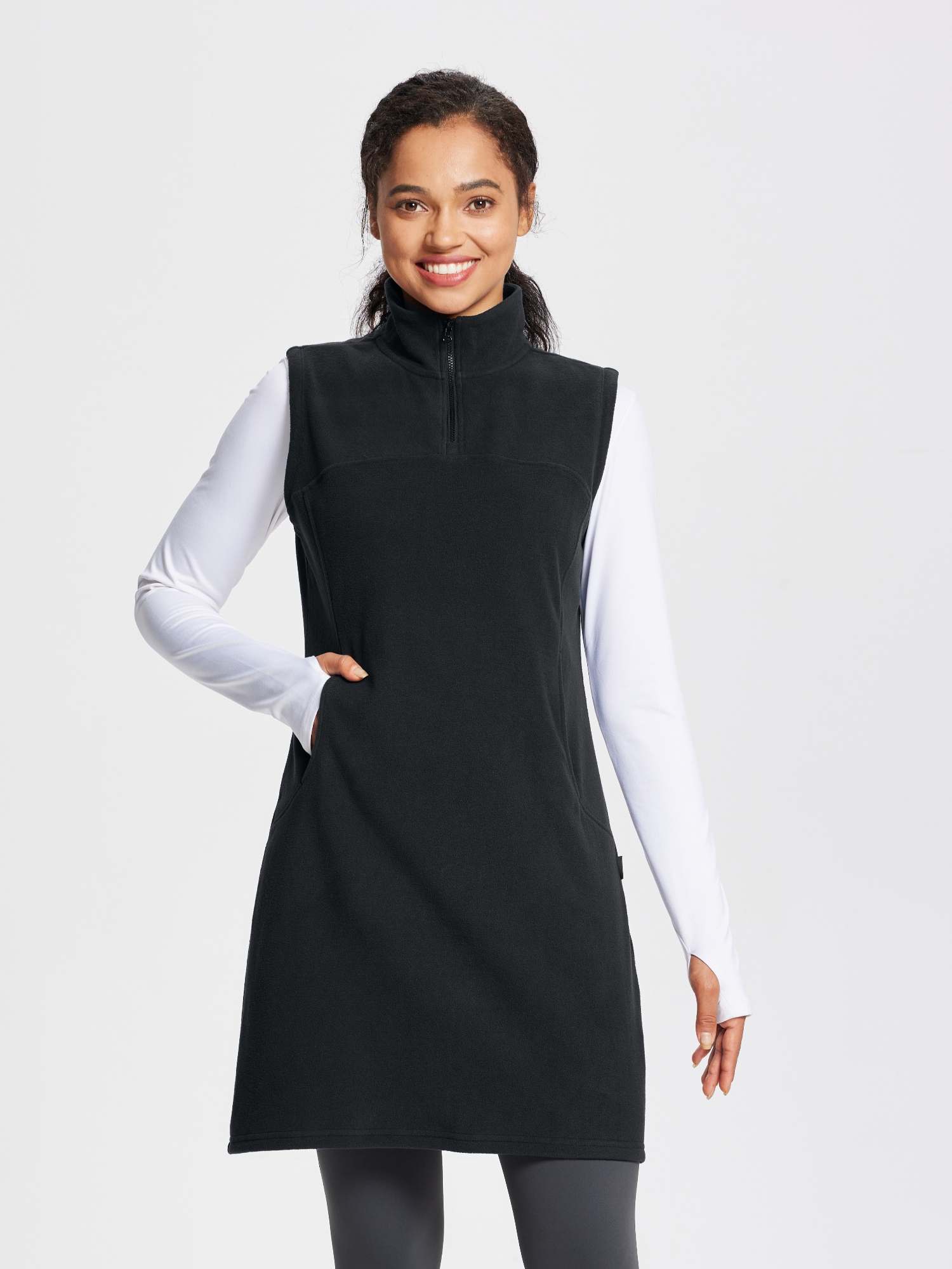 Black sleeveless fleece thermal dress with quarter-zip and pockets, worn over a white long-sleeve shirt. #color_Black