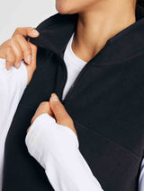 Black sleeveless fleece thermal dress with quarter-zip collar, worn by a woman over a white long-sleeved shirt. #color_Black