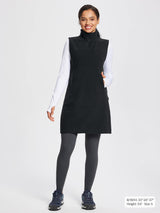 Black sleeveless fleece thermal dress with quarter-zip and pockets, worn over white long-sleeve shirt and grey leggings.